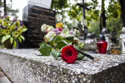 une rose rouge déposé sur le coin d'une pierre tombale