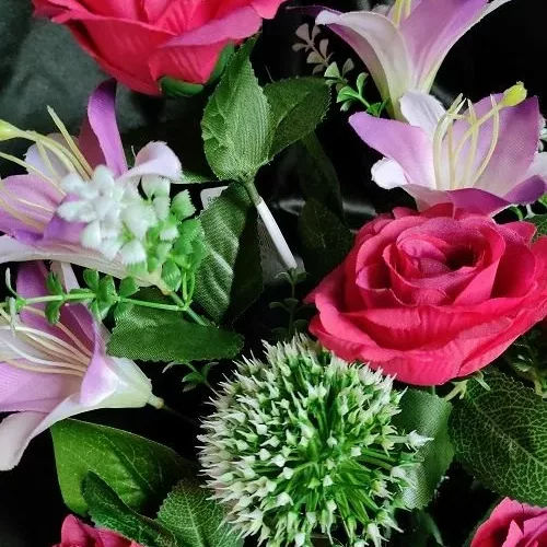 gros plan sur coupe de fleurs artificielles fushia dans pot lesté pour cimetière