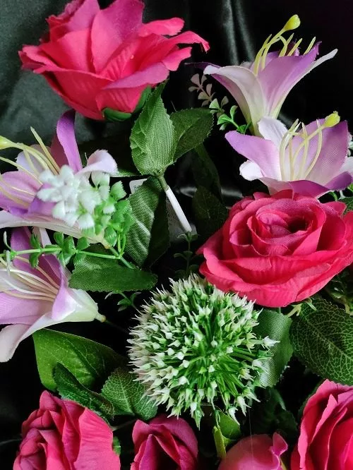 gros plan sur coupe de fleurs artificielles fushia dans pot lesté pour cimetière